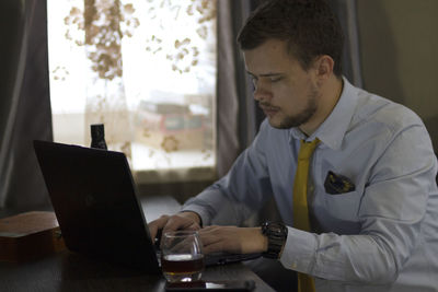 Young man using mobile phone while sitting on table