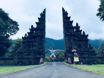 Man levitating over road against old ruins of temple