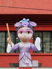 Close-up of white chinese sculpture in purple clothes and flowered tiara