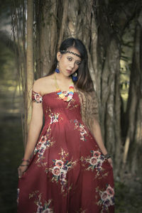 Woman standing by tree trunk in forest