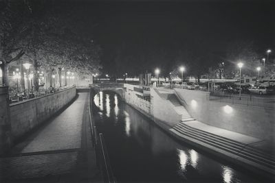 Illuminated bridge over river against sky at night