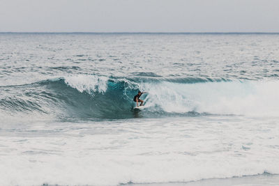 Man surfing in sea against sky
