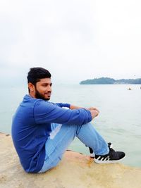 Side view of young man sitting on beach