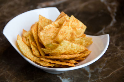 Chips, crisps with seasoning on white plate on the table. snack close up