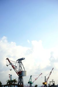 Low angle view of cranes at construction site against sky