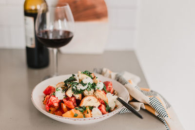 Italian pancanella salad in deep plate. fresh heirloom tomatoes. red wine in glass.