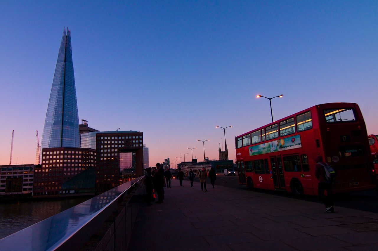 architecture, clear sky, built structure, building exterior, copy space, city, transportation, blue, city life, sunset, the way forward, dusk, outdoors, sky, travel destinations, illuminated, travel, incidental people, bridge - man made structure