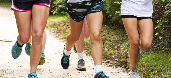 Low section of women running on dirt road