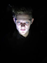 Portrait of young man against black background