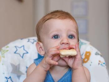 Portrait of cute boy eating baby at home