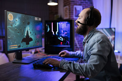 Side view of man playing video game at office