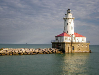 Lighthouse by sea against sky