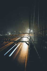 Light trails on bridge in city against sky at night