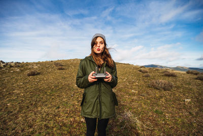 Young woman standing on field against sky