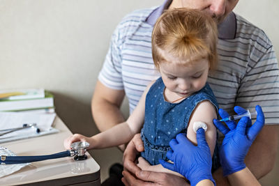 Cropped hand of doctor vaccinating girl in clinic