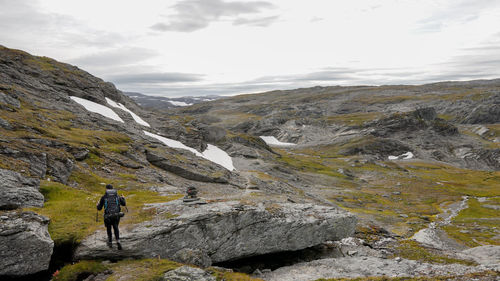 Man hiking through a green mountain landscape on the hardangervidda, norway.