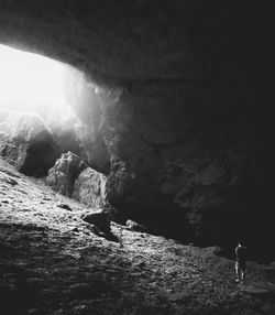 Man standing on rock in cave against sky