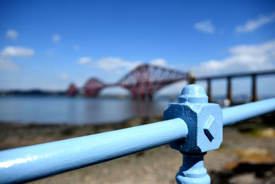 Close-up of metal railing against blue sky