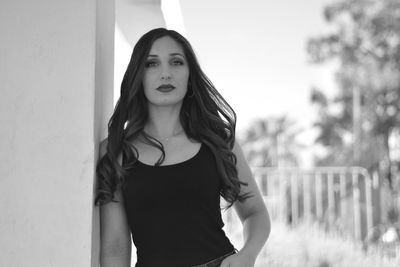 Portrait of beautiful young woman standing against wall