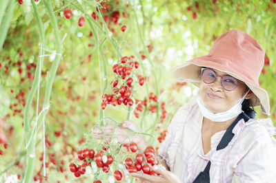 Portrait of woman showing cherry tomatoes on plant