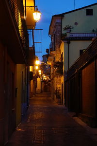 Illuminated walkway amidst buildings at night