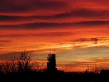 Silhouette buildings against orange sky during sunset