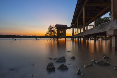 Bridge over river against sky during sunset