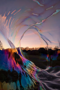 Digital composite image of rainbow over water against sky