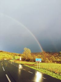Rainbow over road against sky