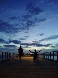 People walking on road against cloudy sky