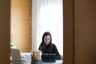 Young woman using phone while sitting on table