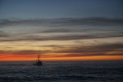 Silhouette sailboat sailing on sea against sky during sunset