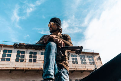 Low angle view of man standing against built structure against sky