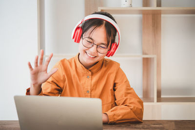 Girl waving while video conferencing over laptop at home