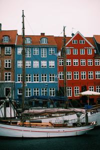 Sailboats moored on canal by buildings against sky in city