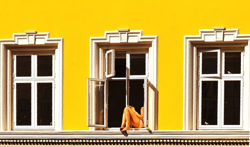 Rear view of woman against yellow building