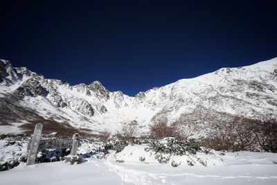 Scenic view of snowcapped mountains against clear blue sky