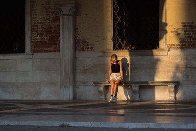 Woman sitting against building