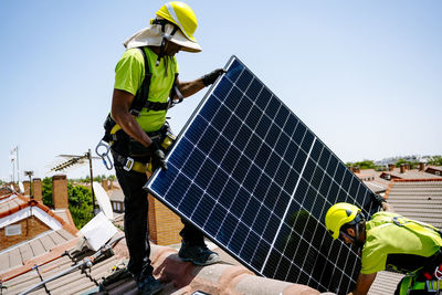 Engineers installing solar panel on sunny day