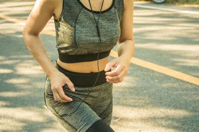 Midsection of woman exercising while standing on street