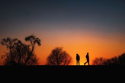 Silhouette couple against orange sky