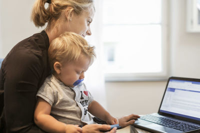 Mother with baby boy using laptop at home