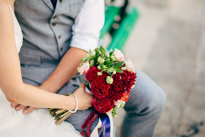 Midsection of man holding flower bouquet