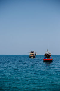 Fishing boat sailing in sea against clear sky