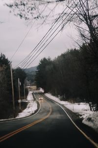 Road amidst trees against sky during winter