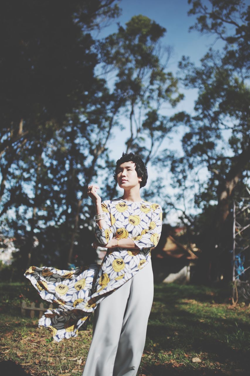 tree, plant, young adult, one person, standing, young women, three quarter length, leisure activity, lifestyles, real people, women, nature, land, field, day, clothing, focus on foreground, growth, outdoors, beautiful woman, fashion, contemplation