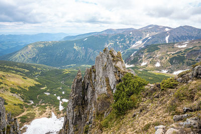 Rock cliff covered with moss against the mountain ranges and sky