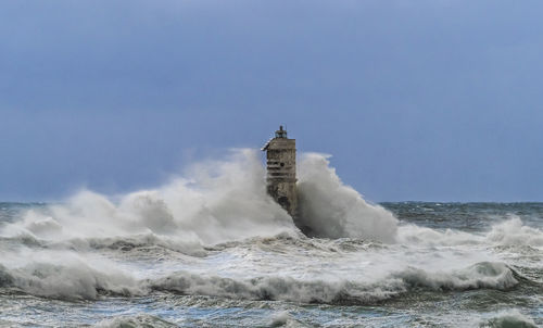 Lighthouse by sea against clear sky