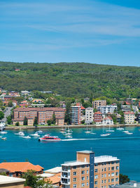 Buildings in city by sea against sky