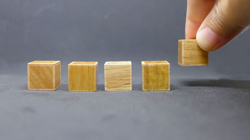 Cropped hand holding wooden toy blocks against gray background